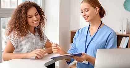 a woman showing a patient how to fill out her forms