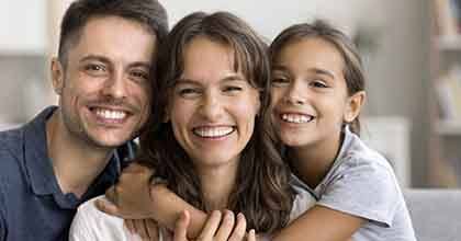 a family of three smiling and sitting on a couch