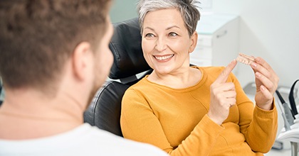 Older woman showing talking to dentist about dental bridges