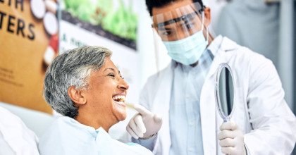 Dentist showing smiling woman reflection in mirror