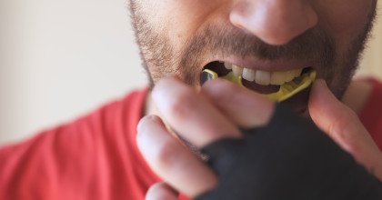 Closeup of man putting on black and yellow mouthguard